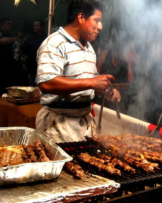 Anticuchero atendiendo la parrilla entre el humo